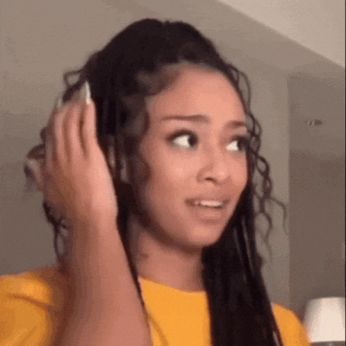 a woman is holding her hair in a ponytail and making a funny face .