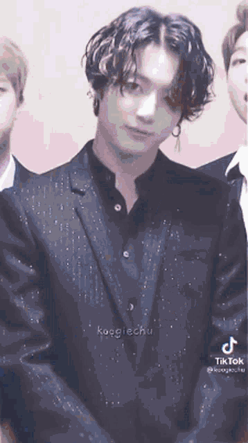 a close up of a person wearing a black suit and a black shirt