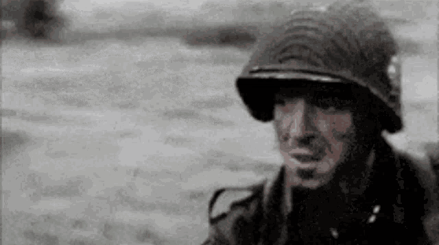 a soldier is wearing a helmet and smoking a cigarette .