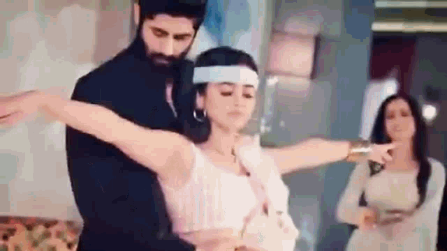 a man and a woman are dancing together in a room . the woman is wearing a headband .