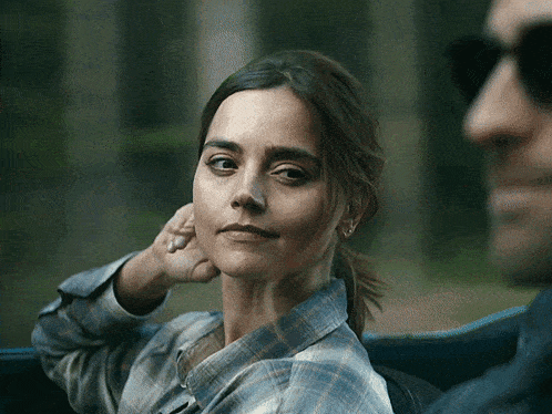 a woman in a plaid shirt is sitting next to a man