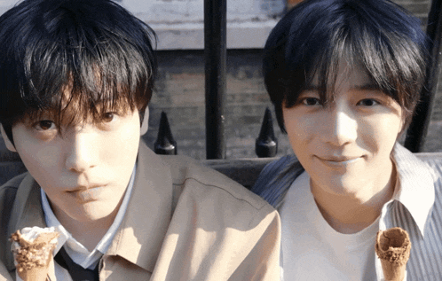two young men are eating ice cream cones and smiling