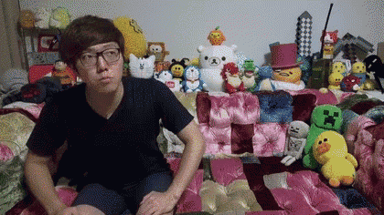 a man is sitting on a couch surrounded by stuffed animals and toys .