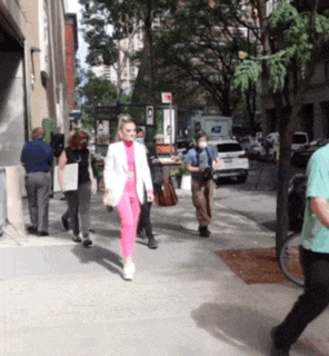 a woman in pink pants is walking down a sidewalk in front of a post office sign