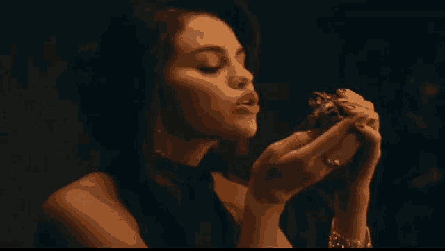 a woman in a black dress holds something in her hands with her mouth open