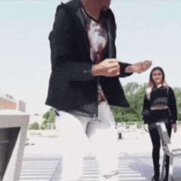 a man in a black jacket is dancing in front of a woman