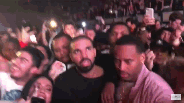 a man in a pink shirt is surrounded by people at a party