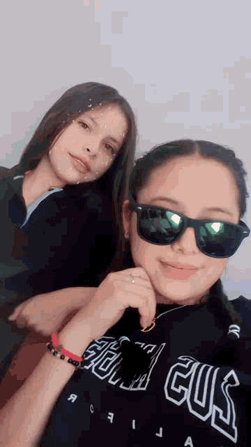 two girls are posing for a picture and one has a shirt that says ' guil gus ' on it