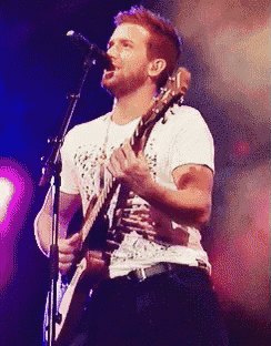 a man is singing into a microphone while holding a guitar