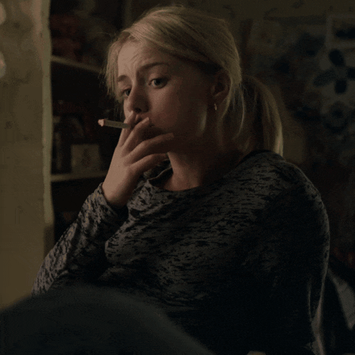 a woman smoking a cigarette while wearing a gray shirt