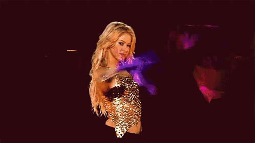a woman in a leopard print top is dancing on a stage with a purple feather .