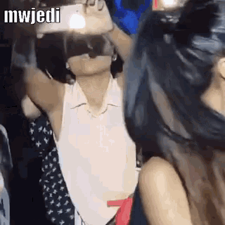 a woman is wearing a virtual reality headset and dancing in a club .