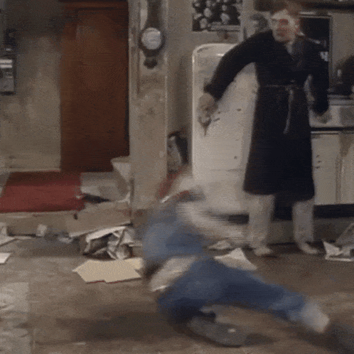 a man in a robe is standing next to a man on the floor