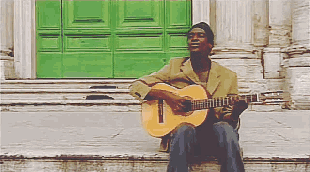 a man is sitting on steps playing a guitar in front of a green door
