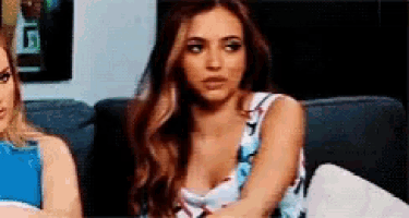 two women are sitting on a couch and one of them is wearing a floral dress .
