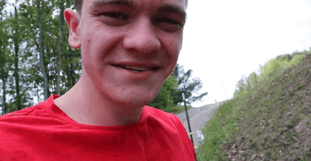 a young man wearing a red shirt is smiling