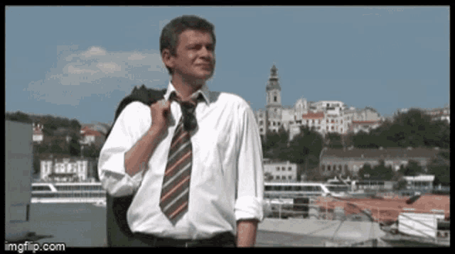 a man wearing a white shirt and tie is standing in front of a city