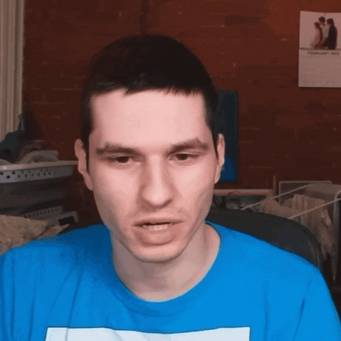 a man wearing a blue shirt has a picture of a couple on the wall in the background