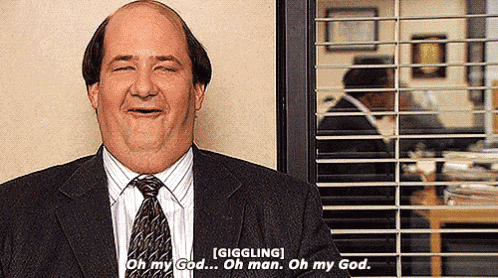 a man in a suit and tie is giggling in front of a window with blinds .