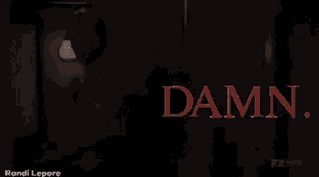 a man is standing in a dark room with the word damn in red letters