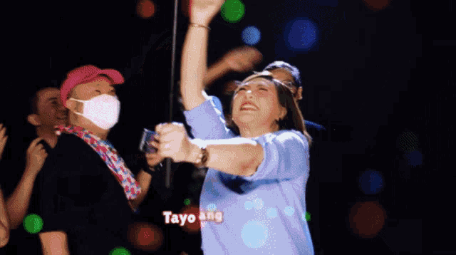 a group of people are dancing in a room with the words tayo ang igaya written on the bottom