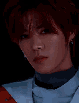 a close up of a person 's face with red hair and earrings .
