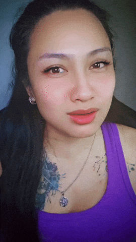a woman wearing a purple tank top has a tattoo on her arm