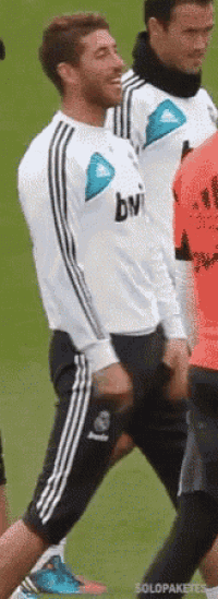 a man in a white shirt with the word bvi on it is walking on a soccer field .