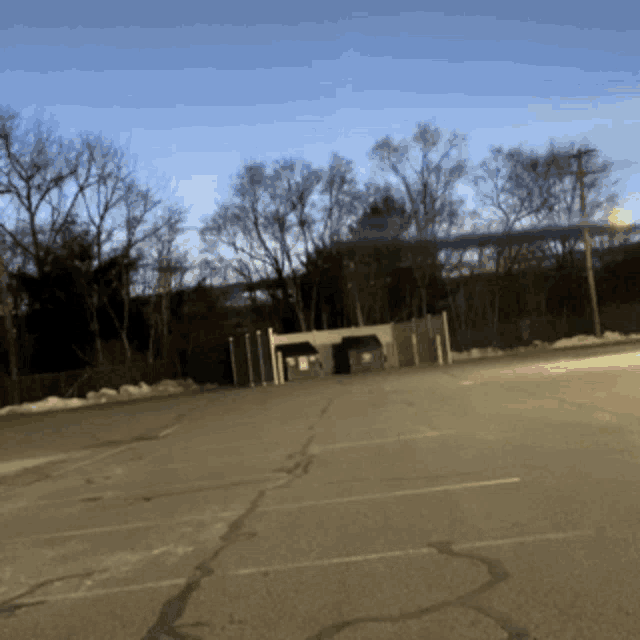 a parking lot with trees in the background and a building in the middle
