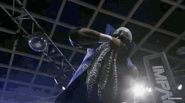 a man in a blue jacket is standing in a boxing ring with his hands on his face .