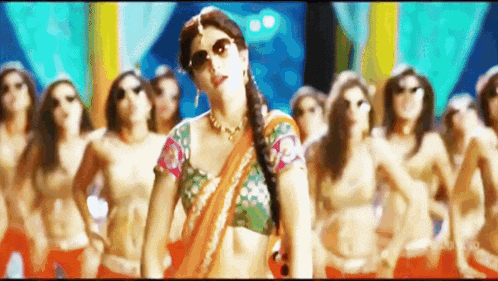a woman in a sari is dancing in front of a crowd of women