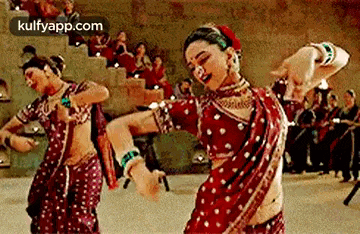 two women are dancing in front of a crowd in a theatre .