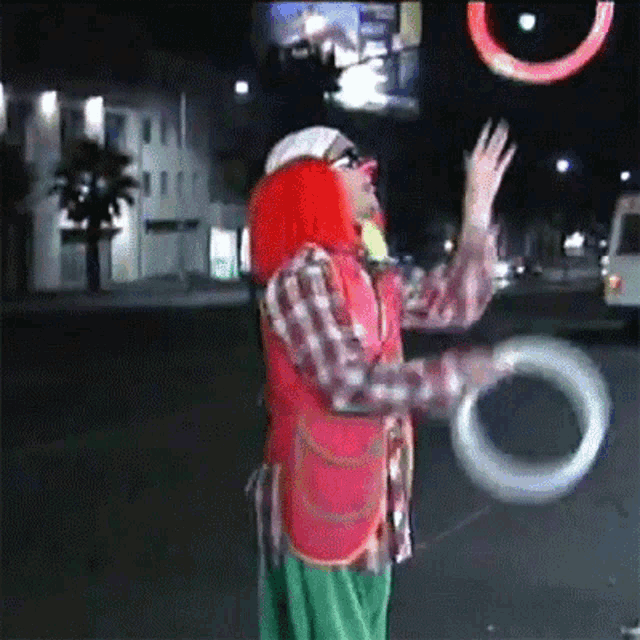 a clown with red hair is juggling a ring