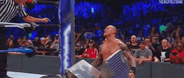 a wrestler is holding a flag in front of a crowd during a wrestling match .