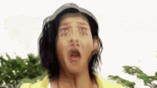 a man in a yellow shirt is making a funny face with his mouth open .
