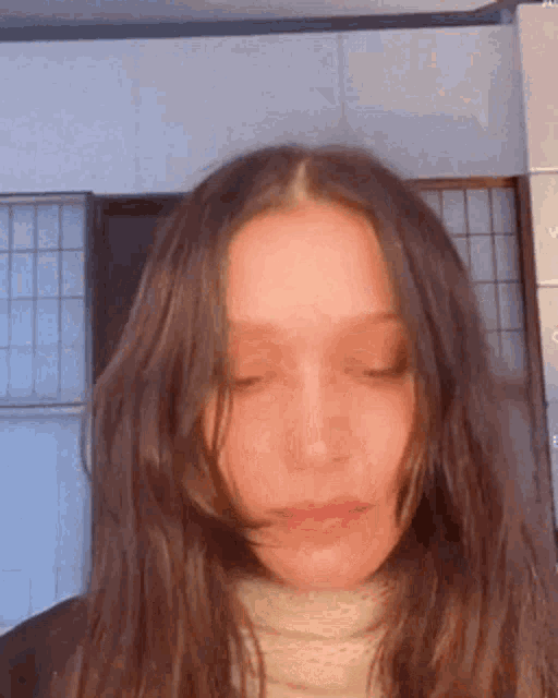 a close up of a woman with long hair wearing a turtleneck sweater .