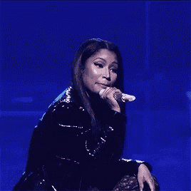 a woman is singing into a microphone while sitting on a stage .