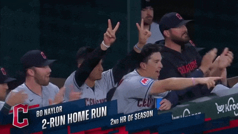 a group of baseball players are sitting in a dugout with a sign that says " 2 run home run "