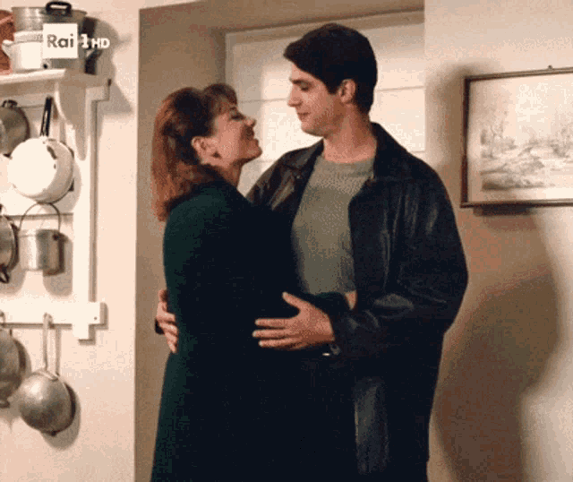 a man and woman are hugging in front of a sign that says rai 3 hd on it