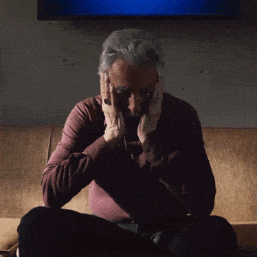 a man sitting on a couch with his head in his hands