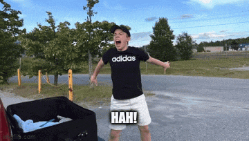 a man wearing a black adidas shirt is standing in front of a suitcase