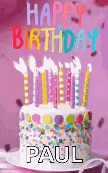 a birthday cake with candles and confetti on it and the name paul written on it .