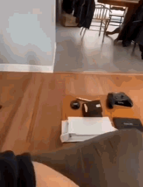 a person is laying on a wooden floor next to a table with papers and a wallet .