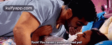 a man is kissing a woman on the forehead while laying on the floor .