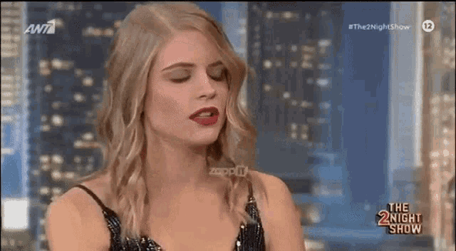 a woman in a black dress is talking on a television show called the night show .