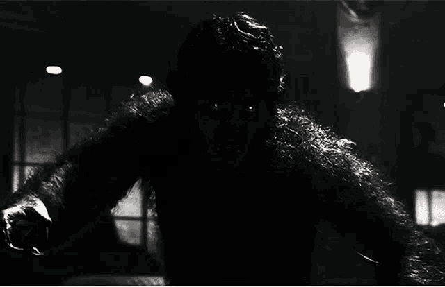 a black and white photo of a werewolf with sharp teeth looking at the camera