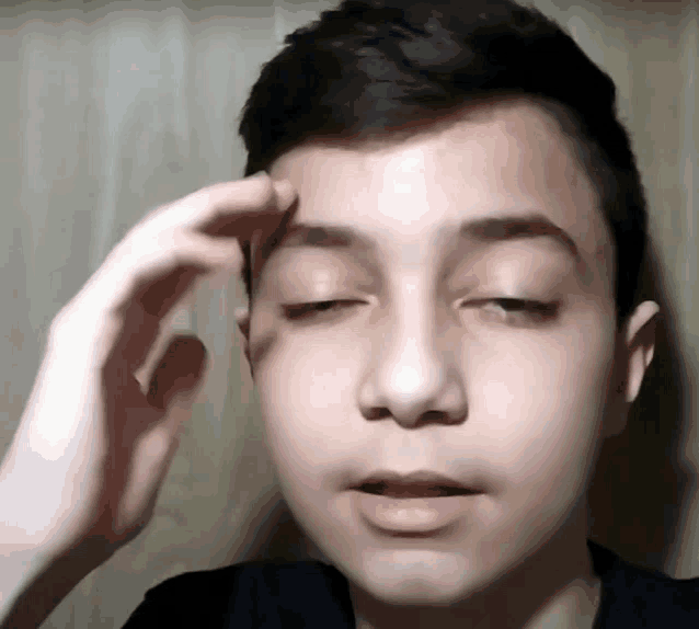 a close up of a person 's face with their eyes closed and their hand on their forehead