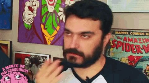a man with a beard is standing in front of a spider-man poster