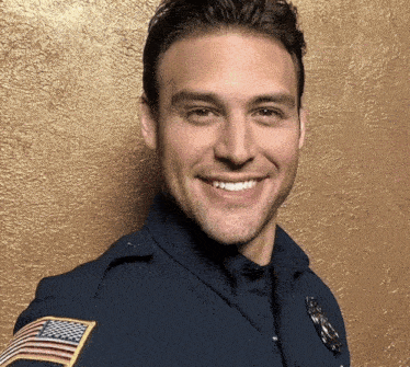 a smiling police officer with an american flag patch on his sleeve