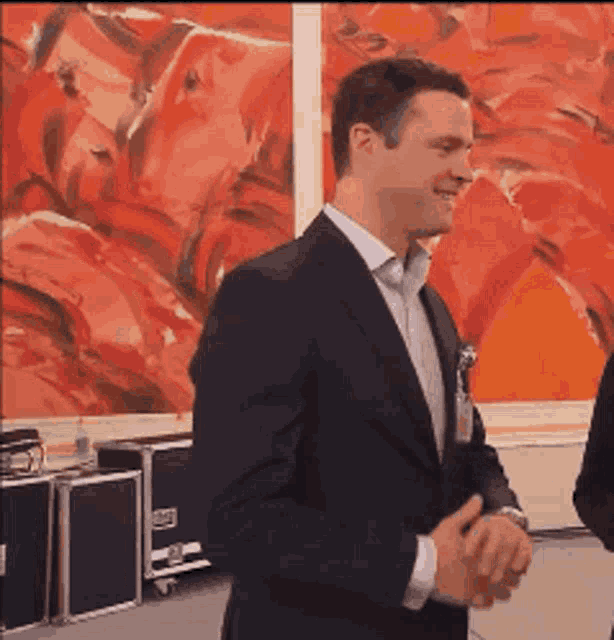 a man in a suit shakes hands with another man in front of a painting